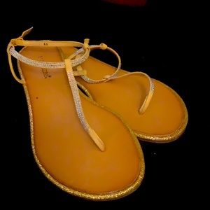 A pair of yellow sparkle sandals.flats